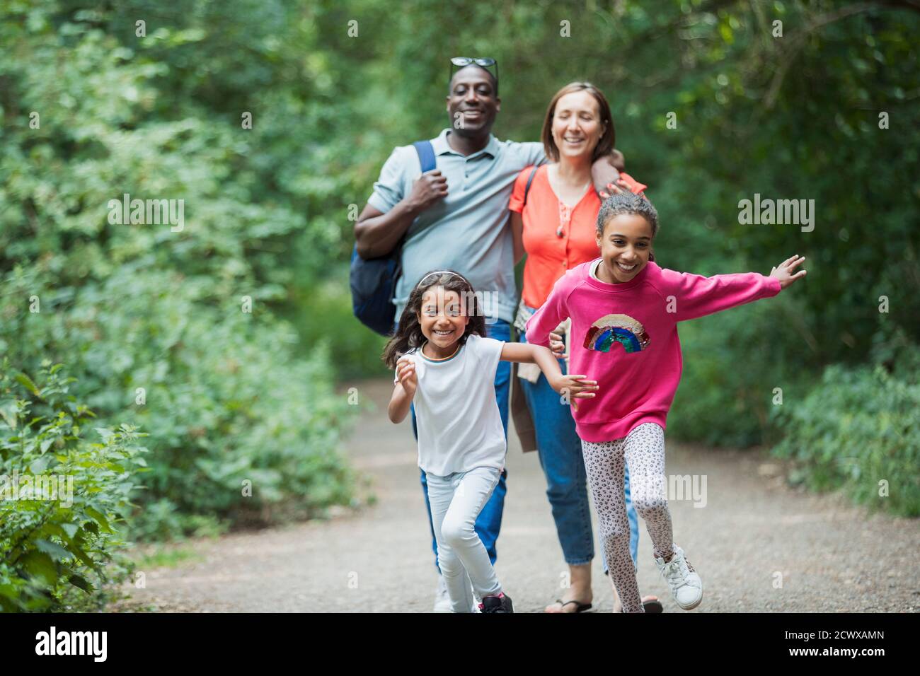 Happy family running and hiking on trail in woods Stock Photo