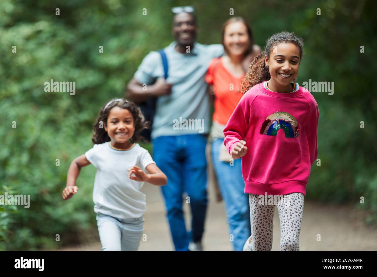 Happy family running and walking on path in woods Stock Photo