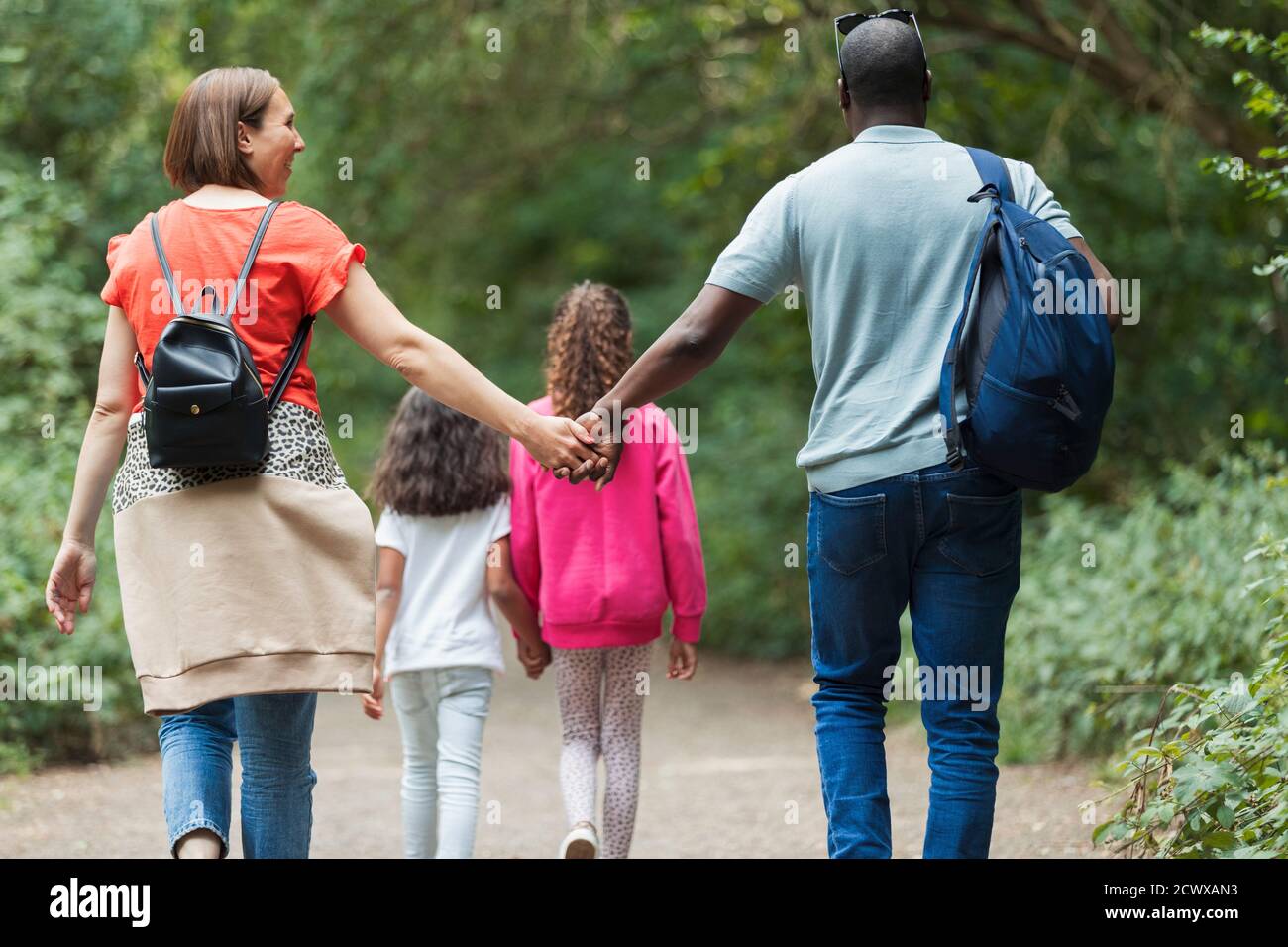 Affectionate family holding hands hiking on trail in woods Stock Photo