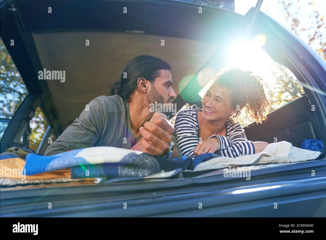 Happy young couple relaxing in back of sunny car Stock Photo