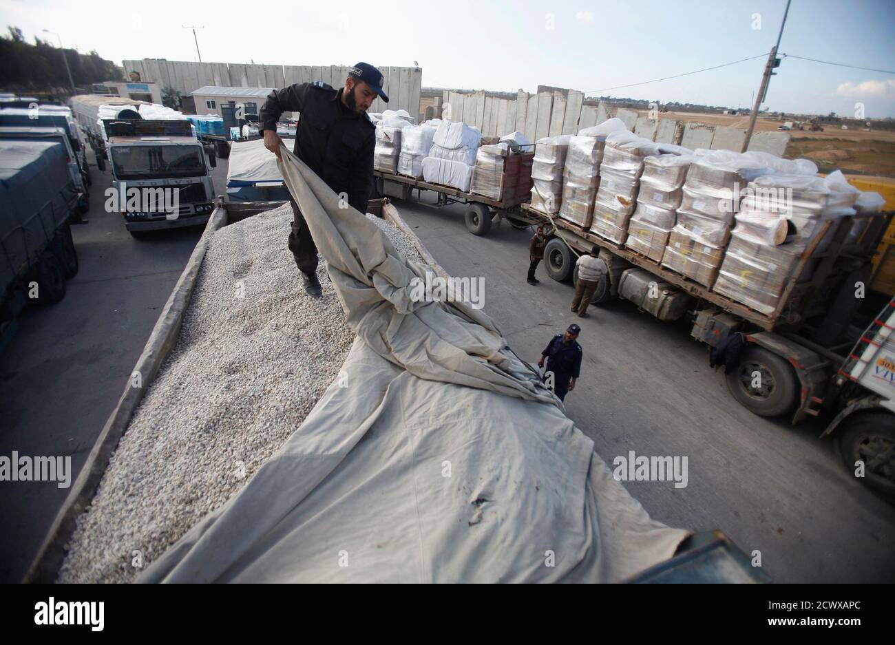 A member of Hamas security forces checks a truck loaded with gravel at the Kerem Shalom crossing between Israel and the southern Gaza Strip December 30, 2012. Israel eased its blockade of Gaza on Sunday, allowing a shipment of gravel for private construction into the Palestinian territory for the first time since Hamas seized control in 2007.   REUTERS/Ibraheem Abu Mustafa (GAZA - Tags: POLITICS) Stock Photo