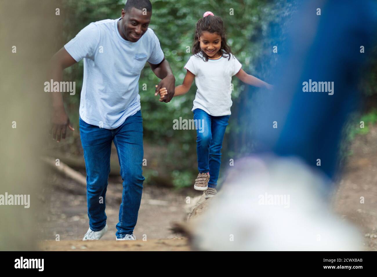 Happy father and daughter running in woods Stock Photo