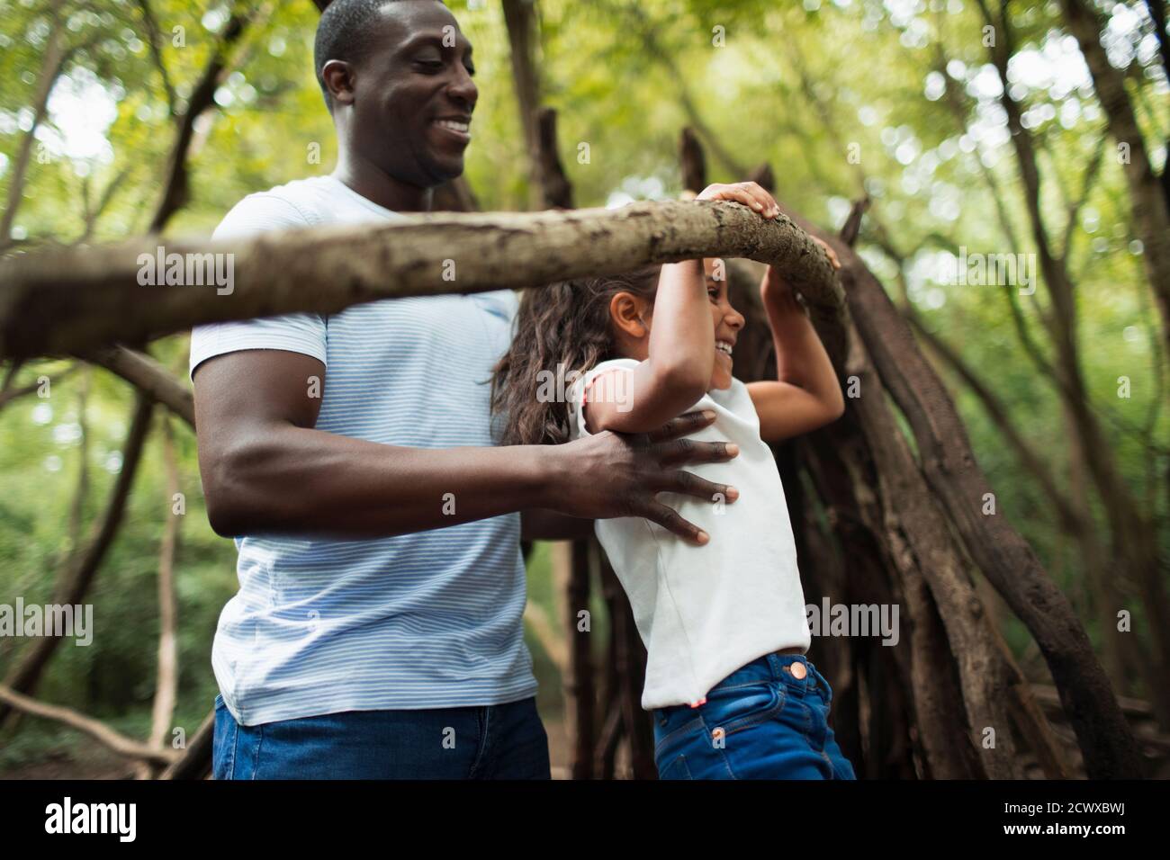 Father and daughter playing with branch in woods Stock Photo