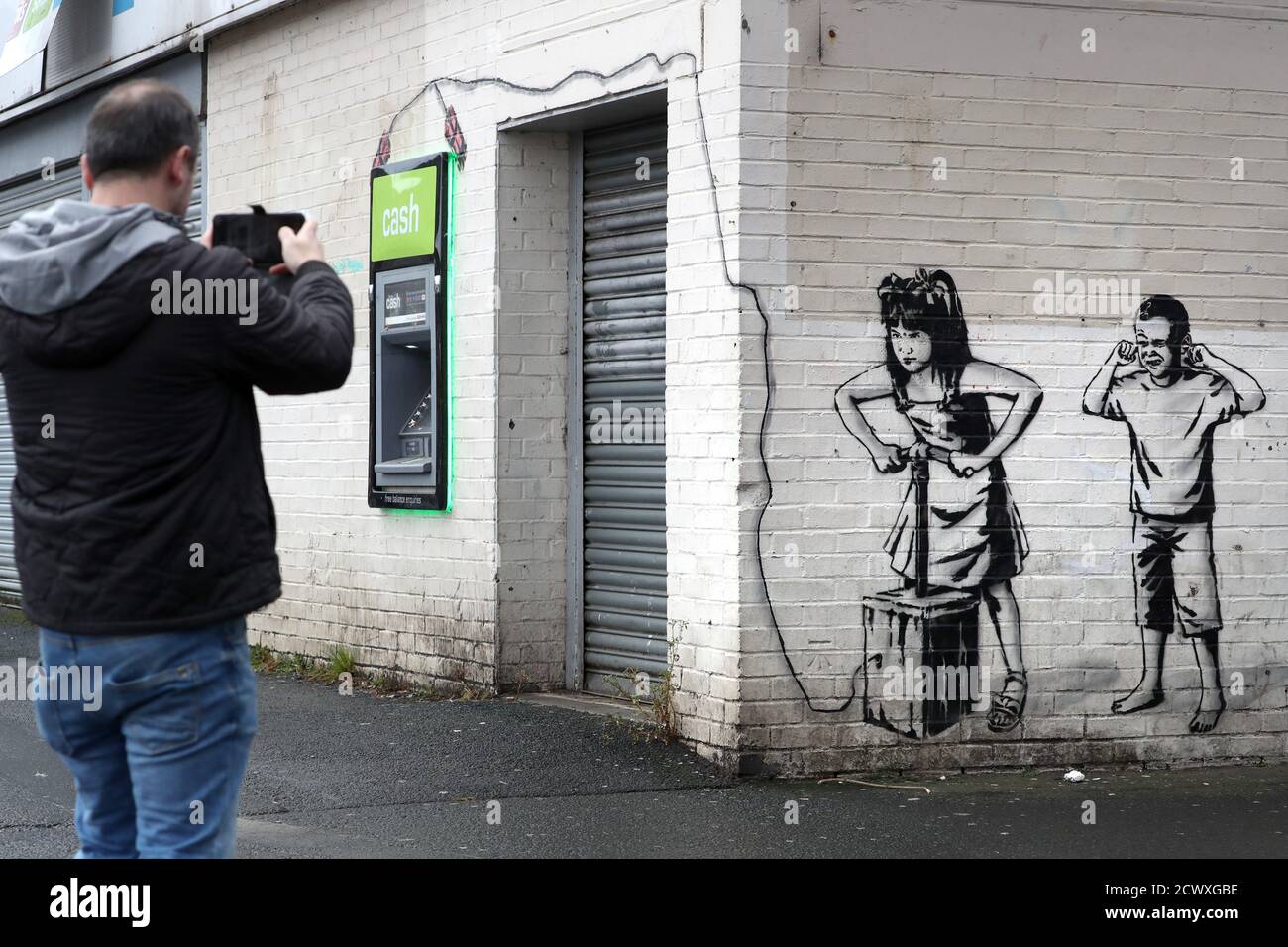 A Man Takes A Picture Of The Art Work By Graffiti Artist The Rebel Bear Which Has Recently Appeared Showing Two Children About To Detonate Explosives At The Cashline At A Shopping