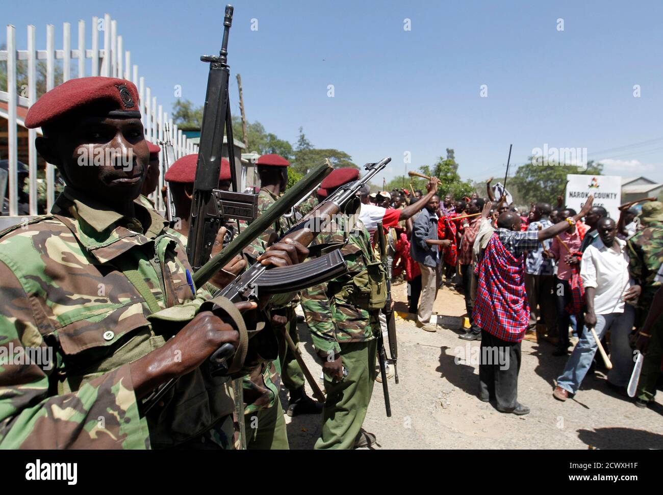 Riot policemen stand guard as they block residents chanting slogans during protests to oust Narok county Governor Samuel Tunai in Narok, Kenya, January 26, 2015.  At least seven people were injured on Monday in clashes between Kenyan police and protesters from the Maasai ethnic group who accuse a local governor of corrupt handling of tourism funds from the Maasai Mara game reserve, the Kenya Red Cross said. REUTERS/Thomas Mukoya (KENYA - Tags: CIVIL UNREST CRIME LAW POLITICS) Stock Photo