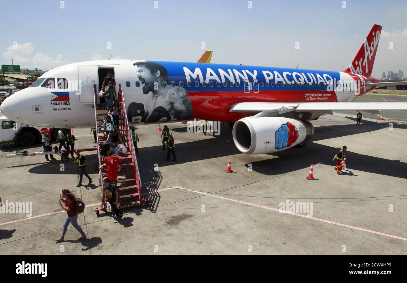 Passengers disembark the AirAsia Philippines Airbus A320 plastered with the image of Filipino boxer Manny Pacquiao as they arrive from Cebu at the domestic airport in Pasay city, metro Manila Apiril 28, 2015. AirAsia Philippines show their support to Pacquiao by painting their aircraft with the boxing icon's name and face, an AirAsia official said. Pacquiao is set to fight American boxer Floyd Mayweather Jr. on May 2 at Las Vegas, Nevada.     REUTERS/Romeo Ranoco Stock Photo