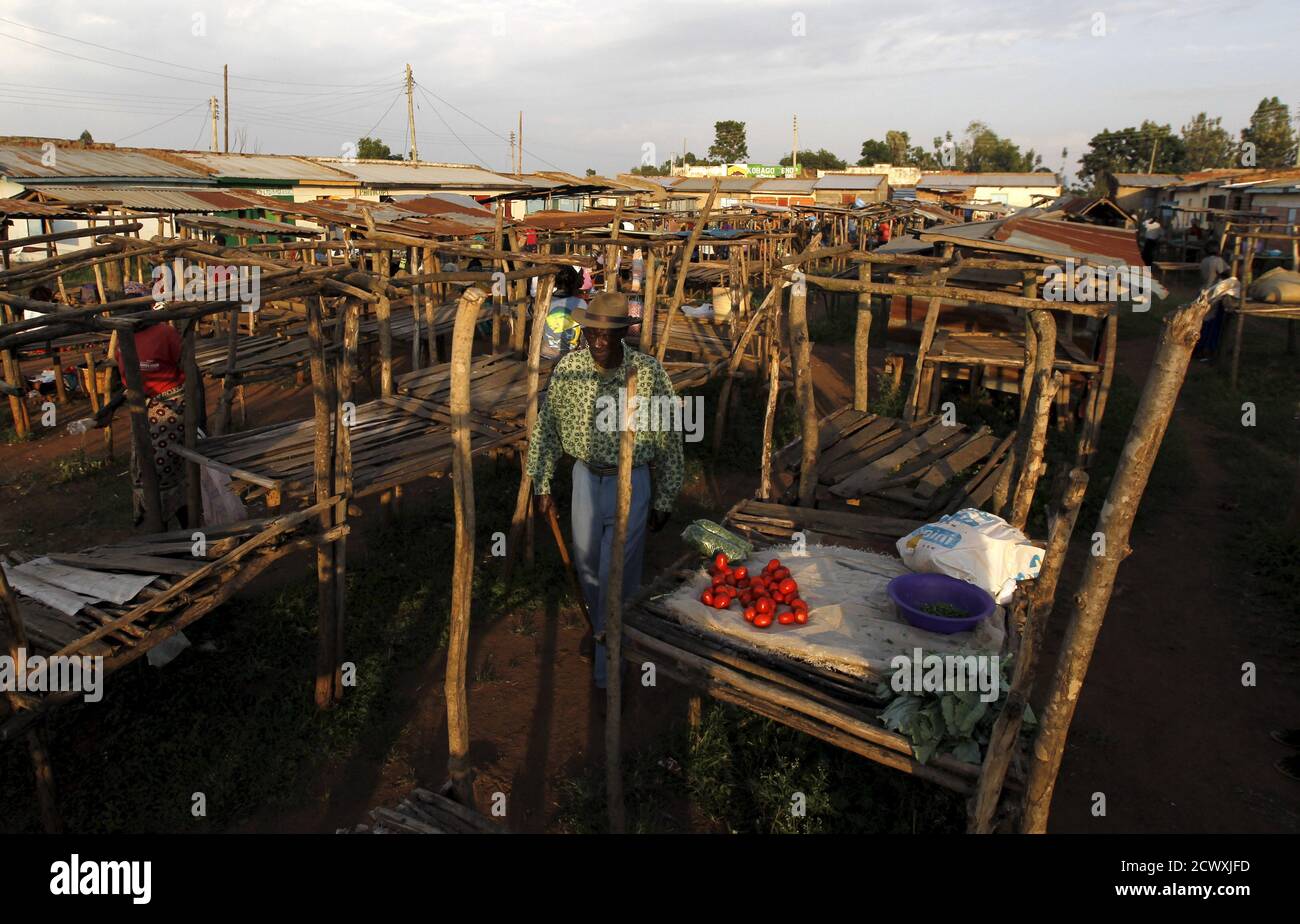 A man walks near wooden stalls at the trading centre in the village of Kogelo, west of Kenya's capital Nairobi, July 15, 2015. U.S. President Barack Obama visits Kenya and Ethiopia later this month. His ancestral home of Kogelo is home to Sarah Hussein Obama, his step-grandmother. The Kenyan village, burial place of Obama's father, features an open-pit goldmine, a pork butcher's, a school named after their most famous son and outdoor market stalls. Villagers get around by motorbike taxi or on foot while a donkey-cart transports water. Children, some of them named Obama in honour of the Preside Stock Photo