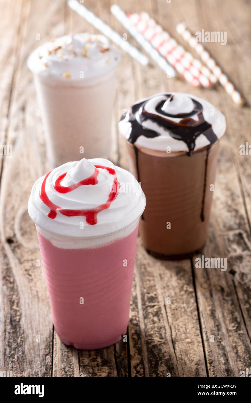 https://c8.alamy.com/comp/2CWXR3Y/strawberry-chocolate-and-white-iced-milkshakes-on-wooden-table-2CWXR3Y.jpg