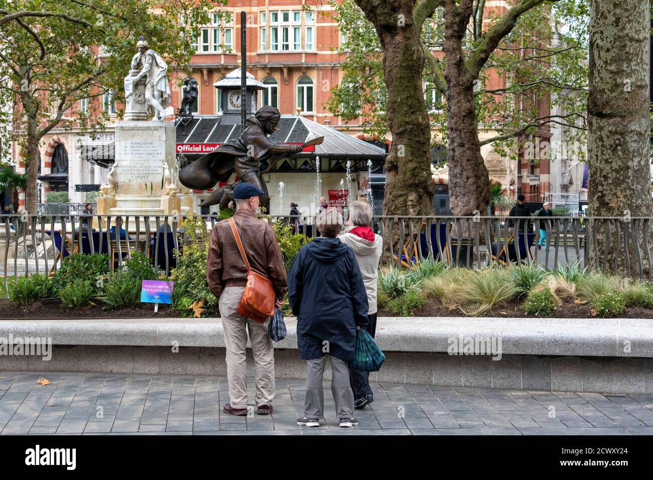 People look at a new statue of Harry Potter in Leicester Square, London which has joined the eight other movie statues already in on display there. Stock Photo