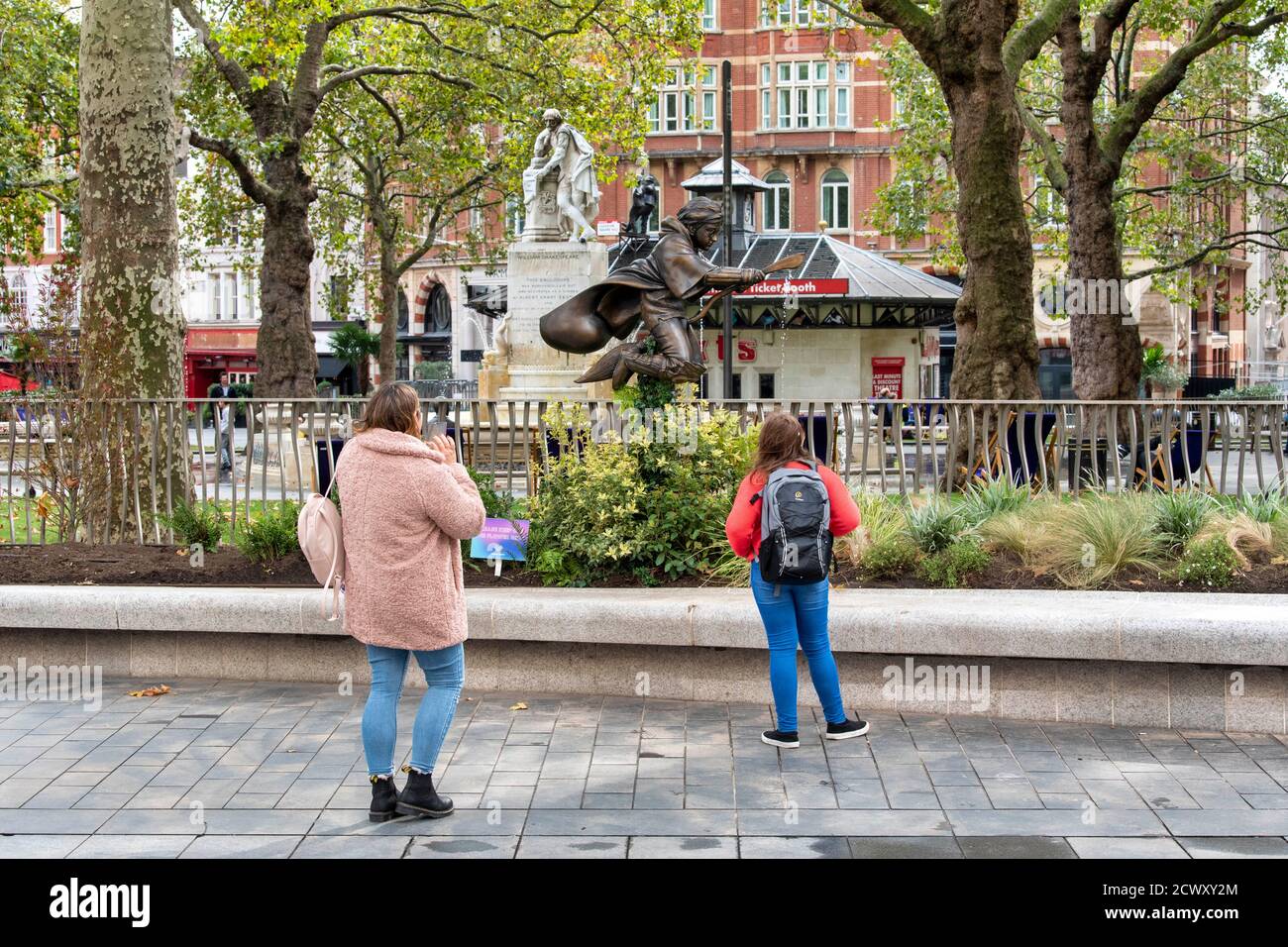 People look at a new statue of Harry Potter in Leicester Square, London which has joined the eight other movie statues already in on display there. Stock Photo