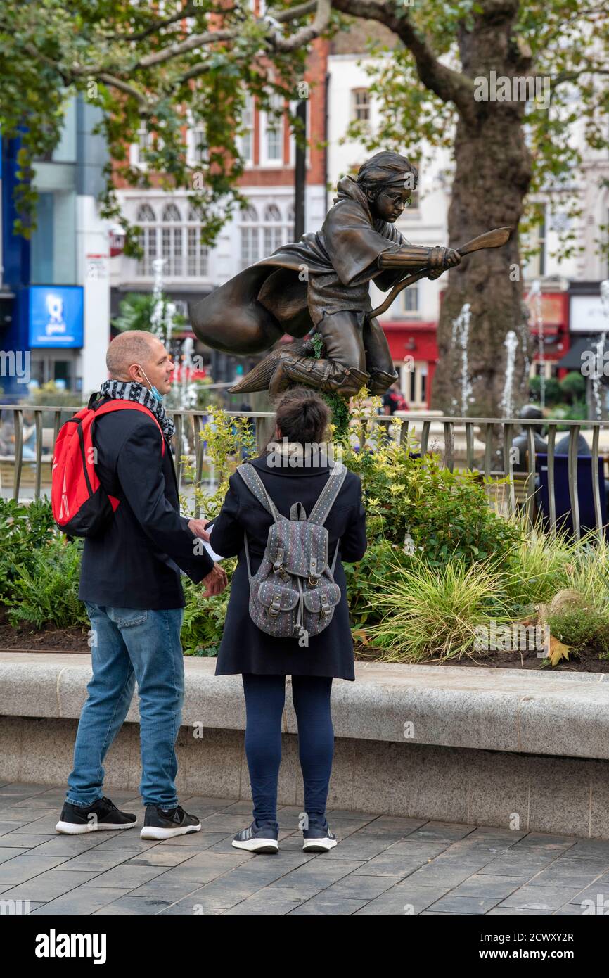 People look at a new statue of Harry Potter in Leicester Square, London which has joined the eight other movie statues already in on display there. Stock Photo