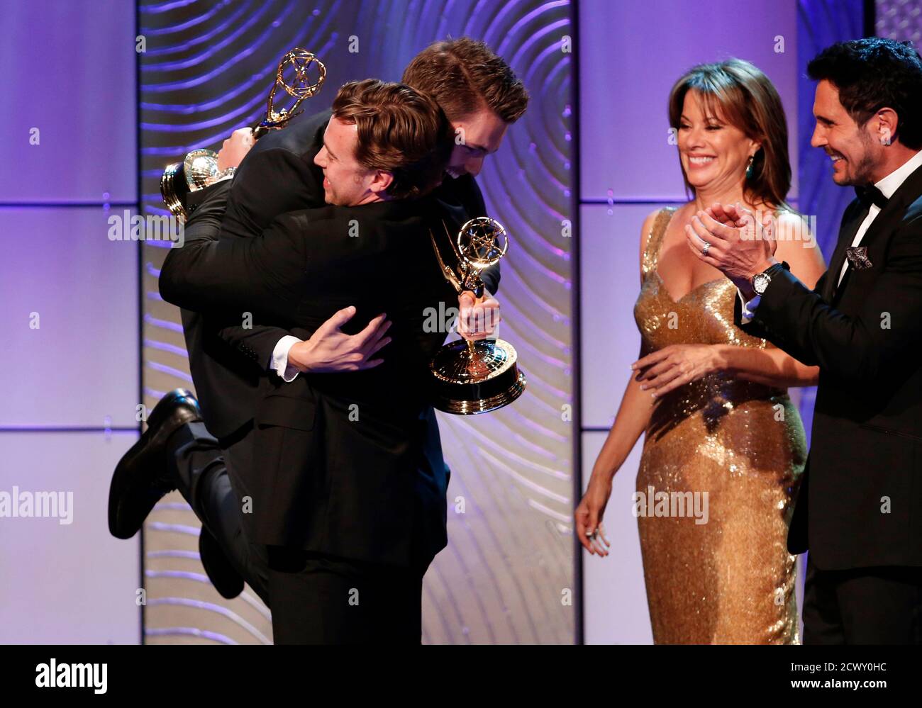Scott Clifton from 'The Bold and the Beautiful' jumps into the arms of Billy Miller from 'The Young and the Restless' as they both celebrate winning the outstanding supporting actor in a drama series award as presenters Nancy Lee Grahn and Don Diamont (L-R) look on during the 40th annual Daytime Emmy Awards in Beverly Hills, California June 16, 2013. REUTERS/Danny Moloshok (UNITED STATES - Tags: ENTERTAINMENT TPX IMAGES OF THE DAY) Stock Photo