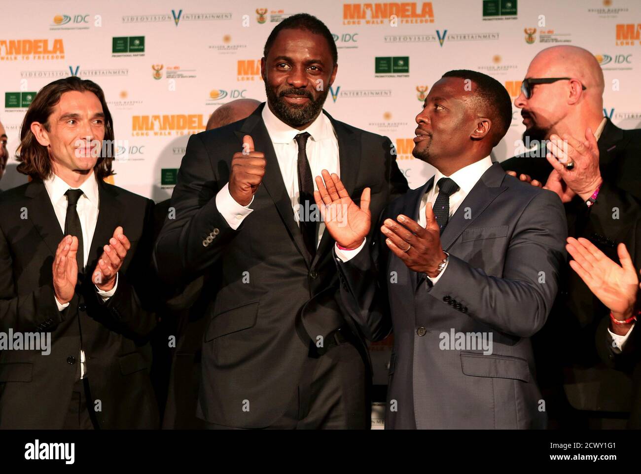 British actor Idris Elba (C), who plays former South African president Nelson Mandela in the movie 'Mandela: Long Walk to Freedom', gestures next to actor Tony Kgoroge who plays anti-apartheid activist Walter Sisulu, as British director Justin Chadwick (L) looks on, at the film's premiere in Johannesburg November 3, 2013. REUTERS/Siphiwe Sibeko (SOUTH AFRICA - Tags: POLITICS ENTERTAINMENT) Stock Photo