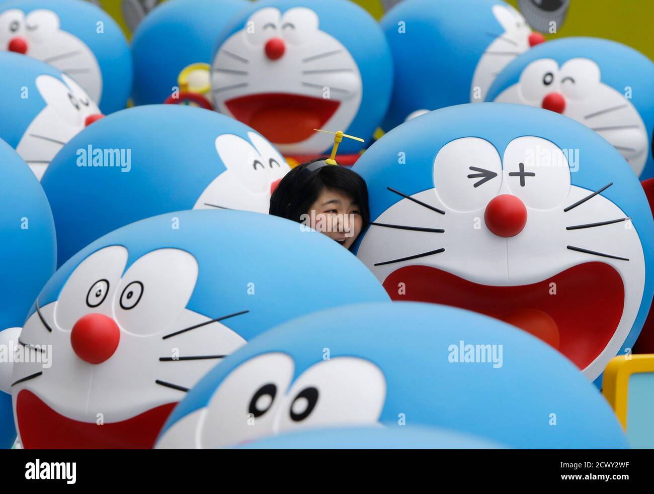 A visitor poses for a photo next to a Doraemon model during an exhibition  in Beijing April 19, 2014. The exhibition, which showcased a hundred models  of the Japanese cartoon character in