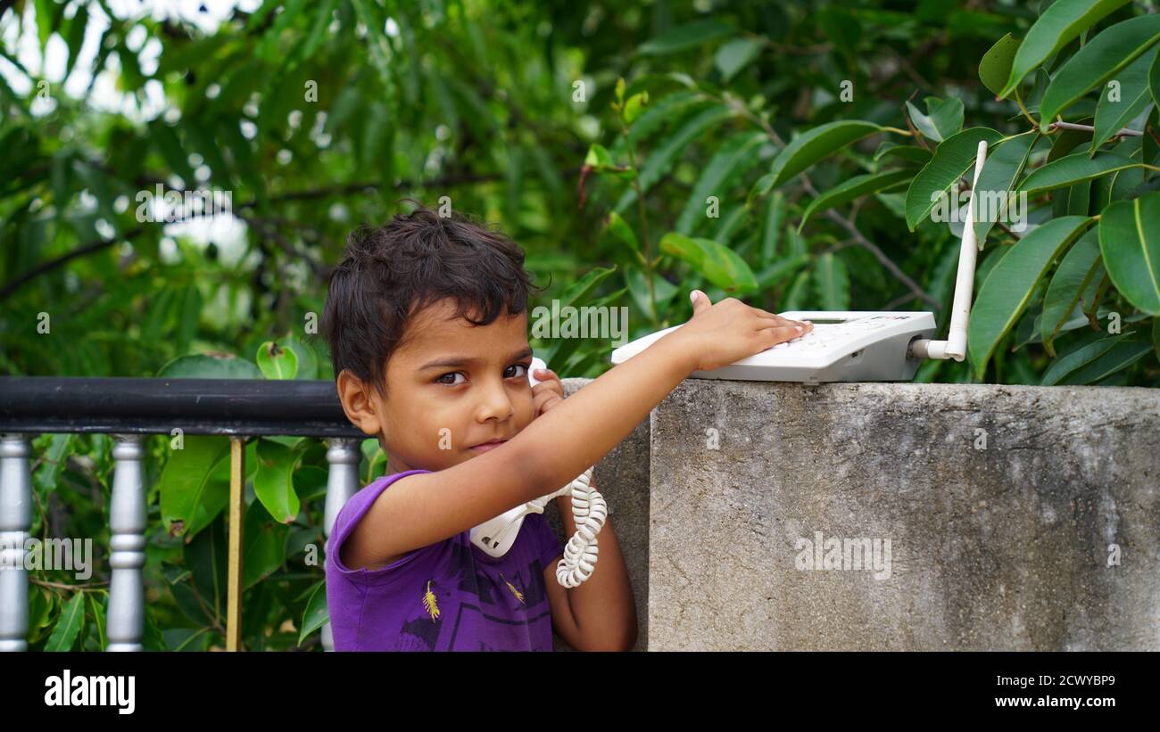 A little Indian girl using telephone. child playing telephone outdoor Stock Photo