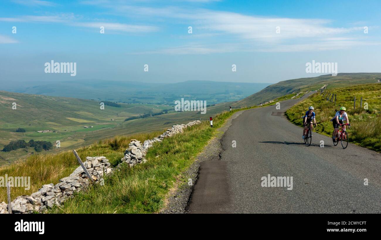 Two women riding road bikes over Fleet Moss, the famous cycling hill climb out of Swaledale, North Yorkshire, England UK Stock Photo