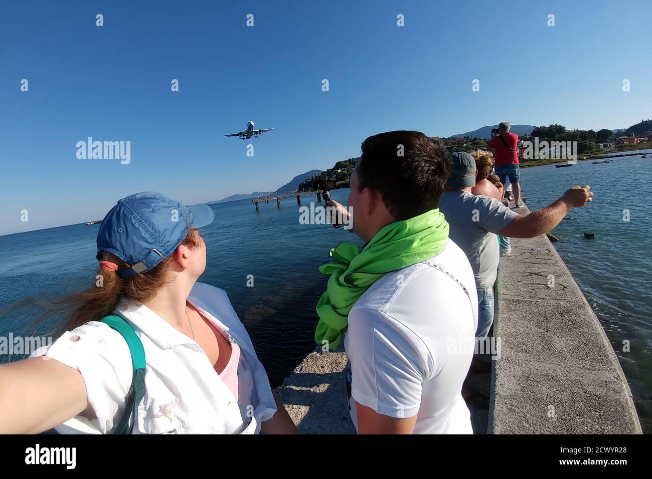 A guy with a girl watching a plane flying by critically low. They are afraid that the plane will now make an unsuccessful landing. Stock Photo