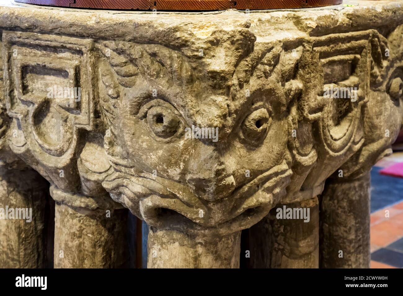 The late Norman font in St Mary's church, South Wootton in North West Norfolk.  It has carved heads on each corner and stands on nine legs. Stock Photo