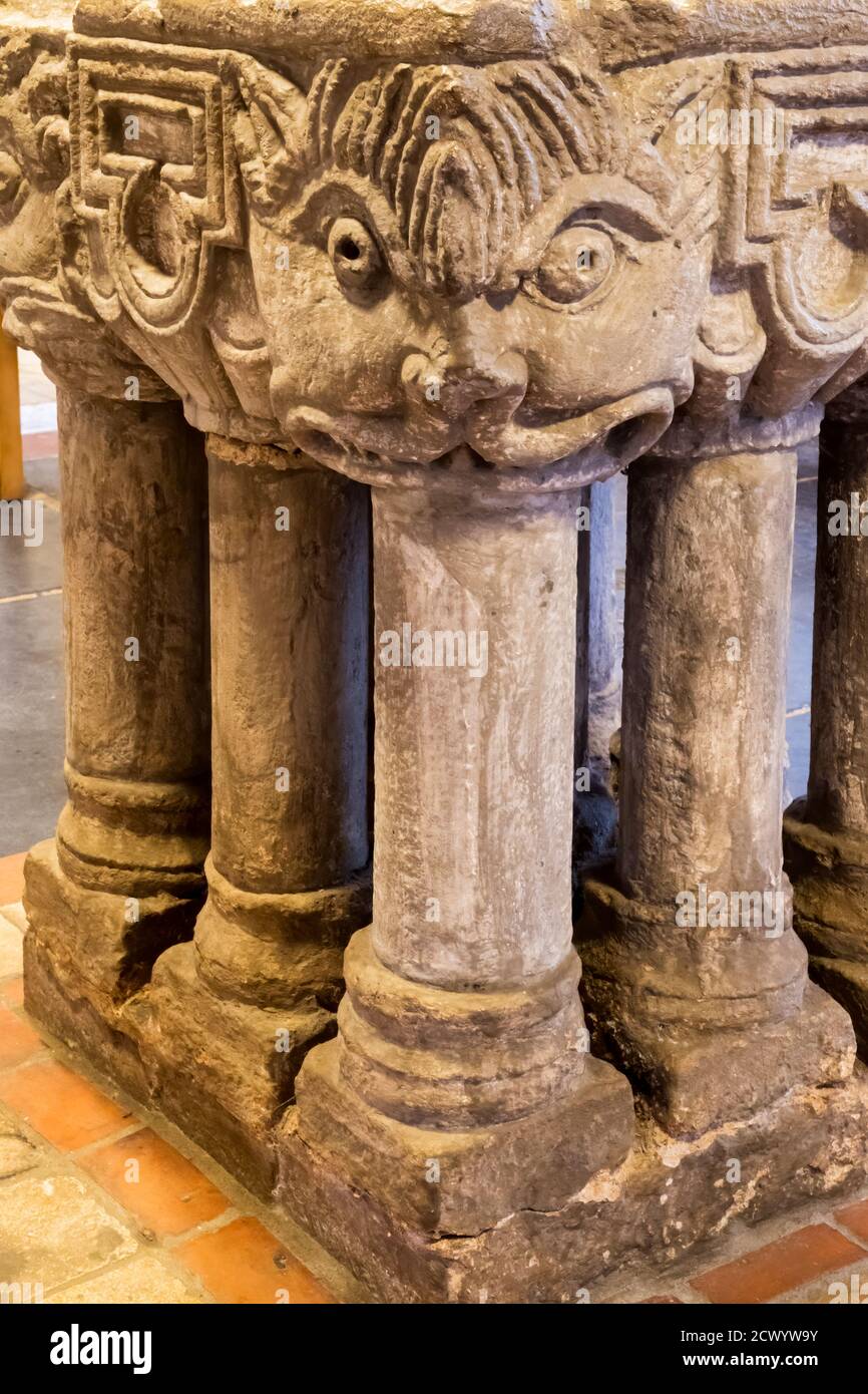 The late Norman font in St Mary's church, South Wootton in North West Norfolk.  It has carved heads on each corner and stands on nine legs. Stock Photo