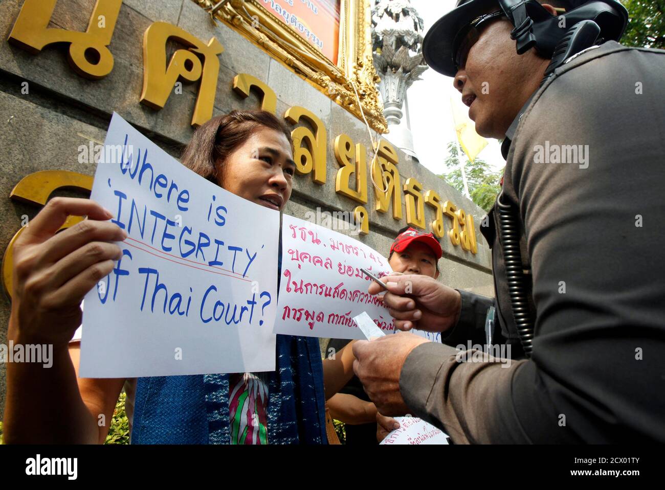 A police officer speaks with an activist during a protest in front of the Thai Criminal court in Bangkok January 25, 2013. The activists were protesting against the lese majeste law which jailed a former Thai magazine editor for 10 years on Wednesday for insulting the royal family, a sentence that drew condemnation from international rights groups and the European Union. Somyot Prueksakasemsuk was found guilty of publishing articles defaming King Bhumibol Adulyadej in 2010 when he was editor of a magazine devoted to self-exiled former Prime Minister Thaksin Shinawatra.  REUTERS/Chaiwat Subpras Stock Photo