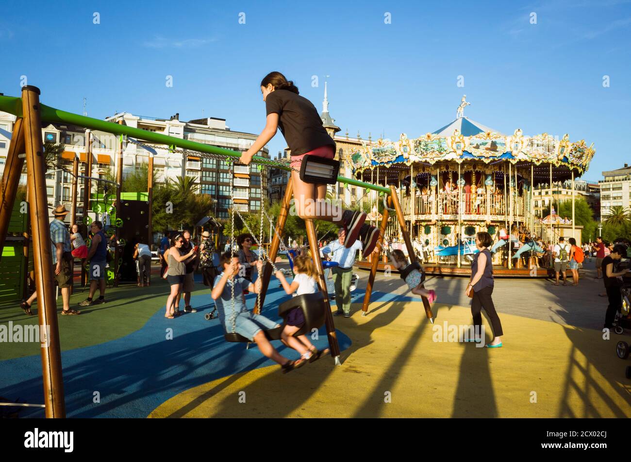 Donostia, Gipuzkoa, Basque Country, Spain - July 15th, 2019 : Children play in a swing next to the vintage style merry-go-round. Stock Photo