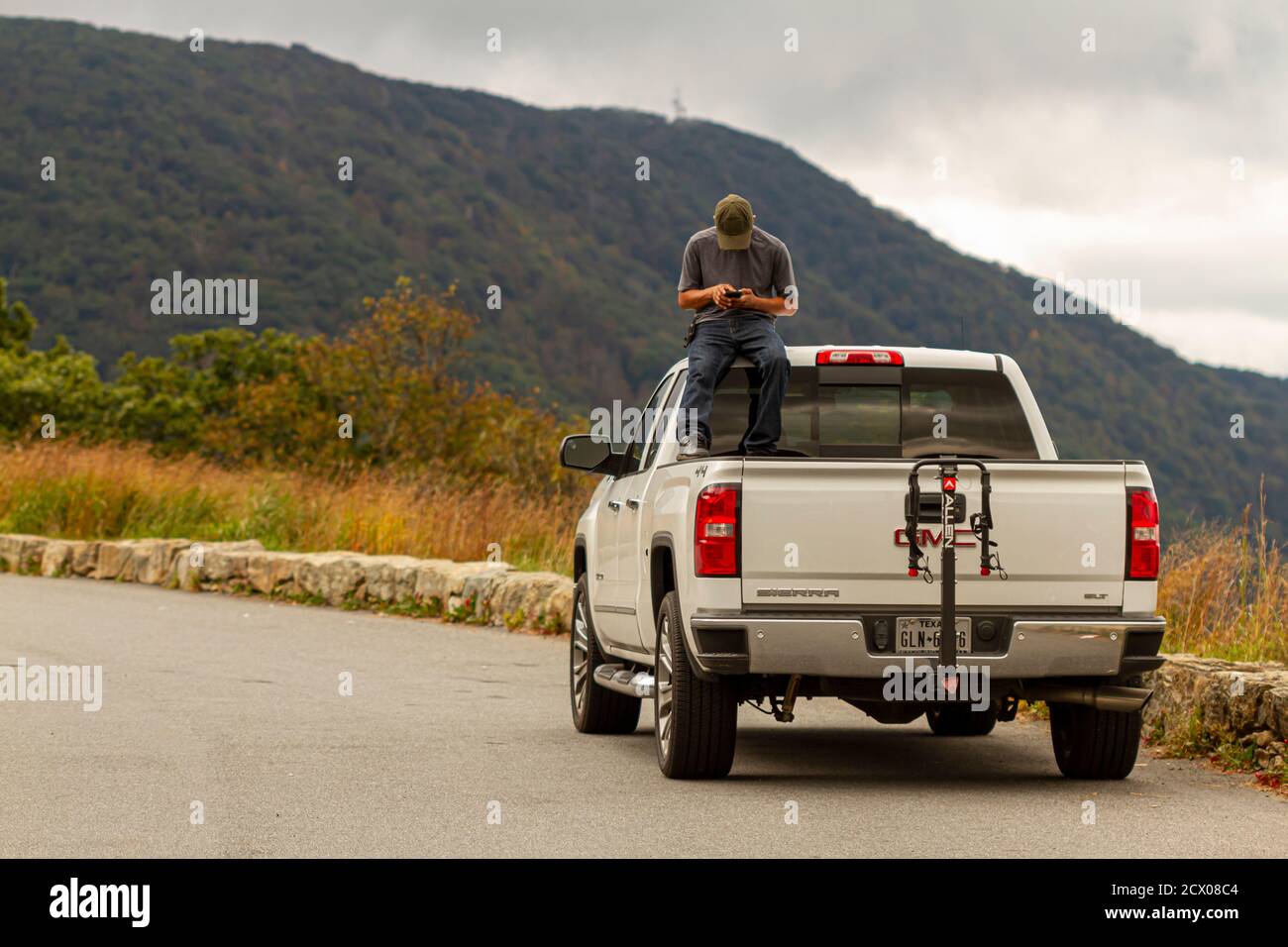 Shenandoah Valley, VA, USA, 09/27/2020: A man is inside trunk of a white GMC sierra pickup truck  sitting on the driver cabin playing with his phone. Stock Photo