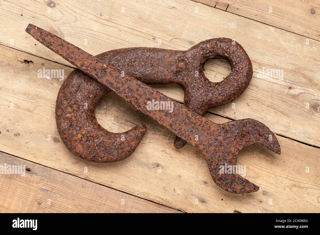 An old rusty hook and spanner on a wooden surface Stock Photo