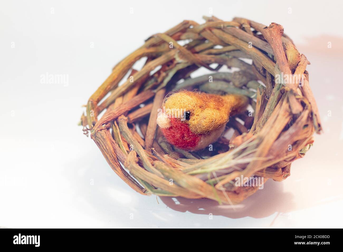 Selective shallow focus on a tiny needle felted robin in handmade basket nest Stock Photo