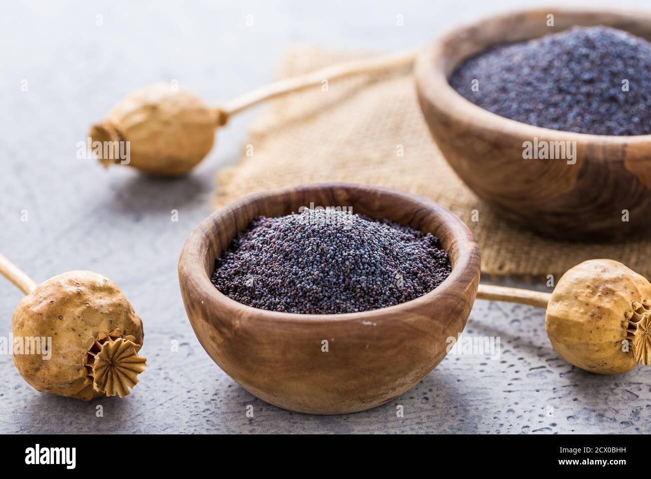 Poppy seeds in small bowl with poppy heads on wooden background. Baking  ingredients Stock Photo - Alamy