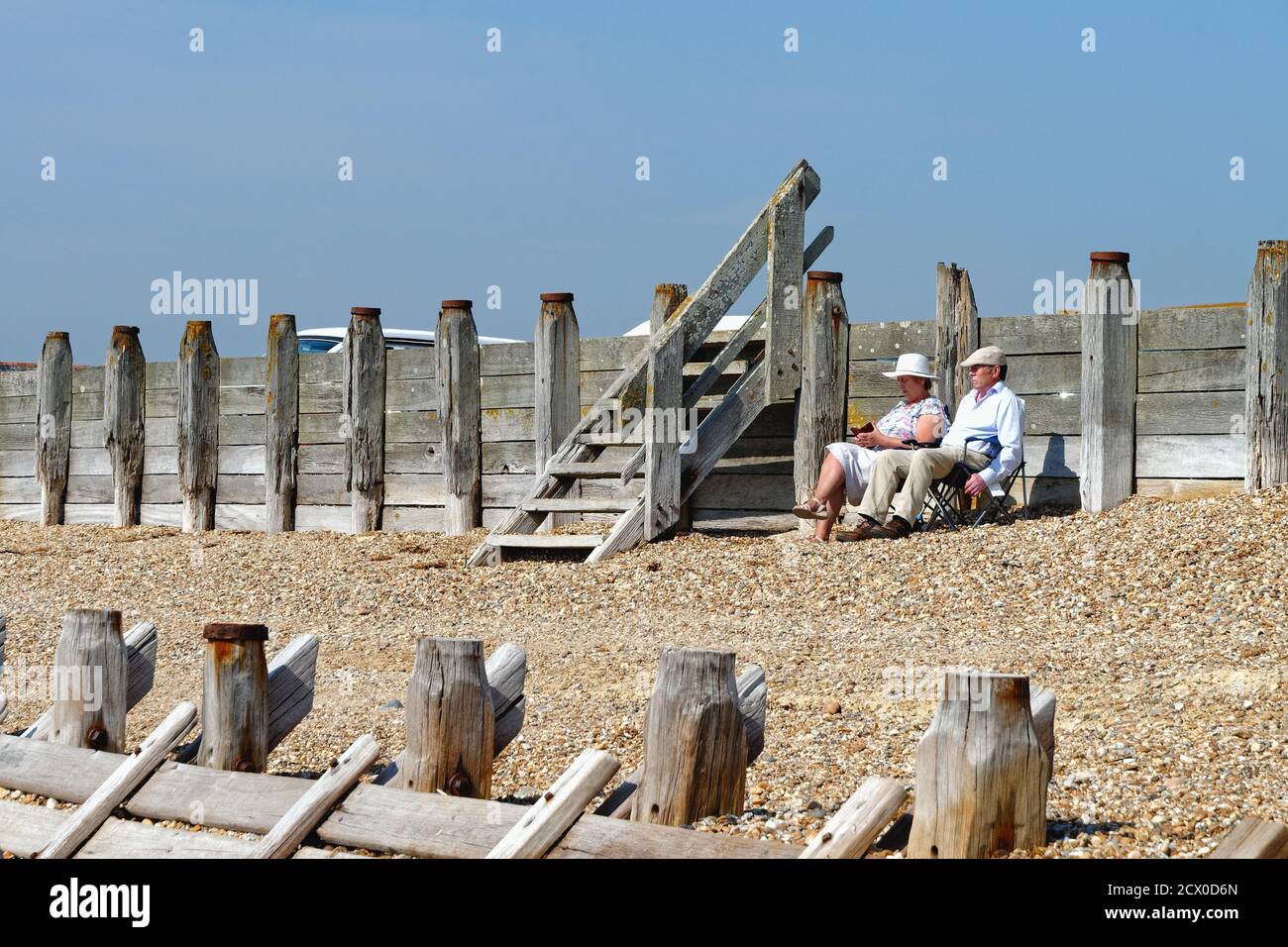 Elderly couple sitting on beach enjoying  a hot summers day at Hayling Island Hampshire England UK Stock Photo