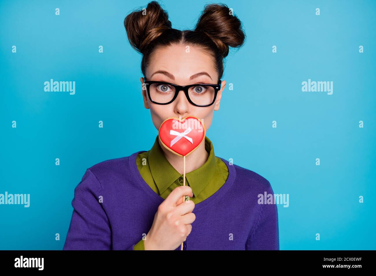 Close-up portrait of her she nice attractive pretty funny schoolgirl closing mouth caramel candy bow heart shape isolated on bright vivid shine Stock Photo