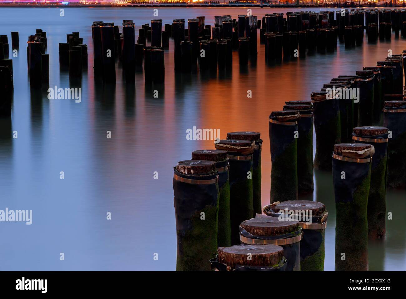 Long exposure at the Brooklyn Bridge Park in New York City across east river with wood pilings water NY USA Stock Photo