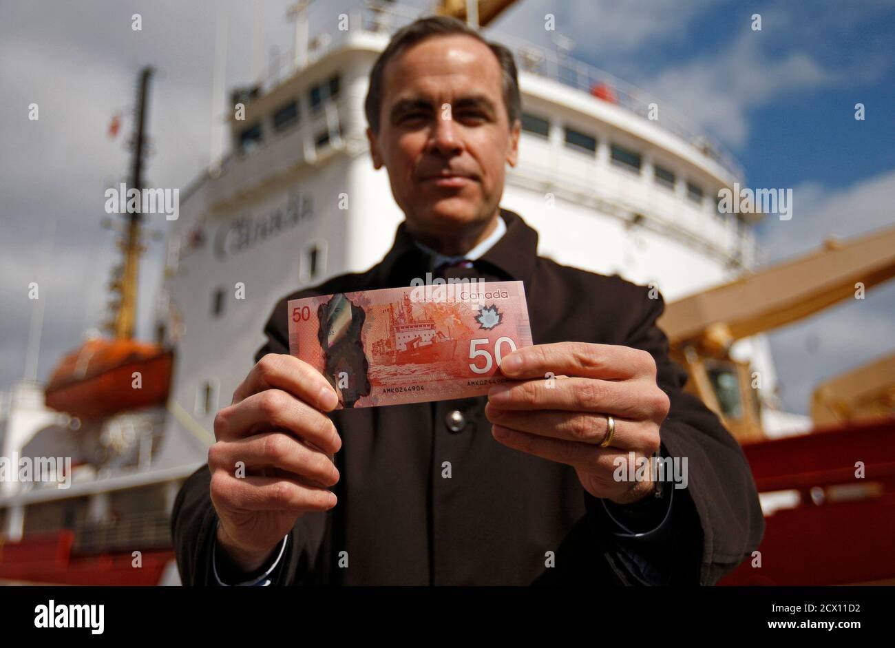 Bank of Canada Governor Mark Carney presents the new Canadian 50 dollar bill, made of polymer, in front of the CCGS Amundsen, the Arctic research vessel depicted on the back of the new bill, in Quebec City, March 26, 2012. REUTERS/Mathieu Belanger (CANADA - Tags: BUSINESS) Stock Photo