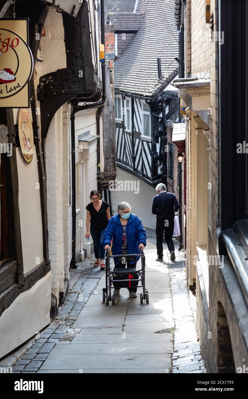An elderly person wearing a face-covering climbs Grope Lane, Shrewsbury during the 2020 coronavirus pandemic Stock Photo