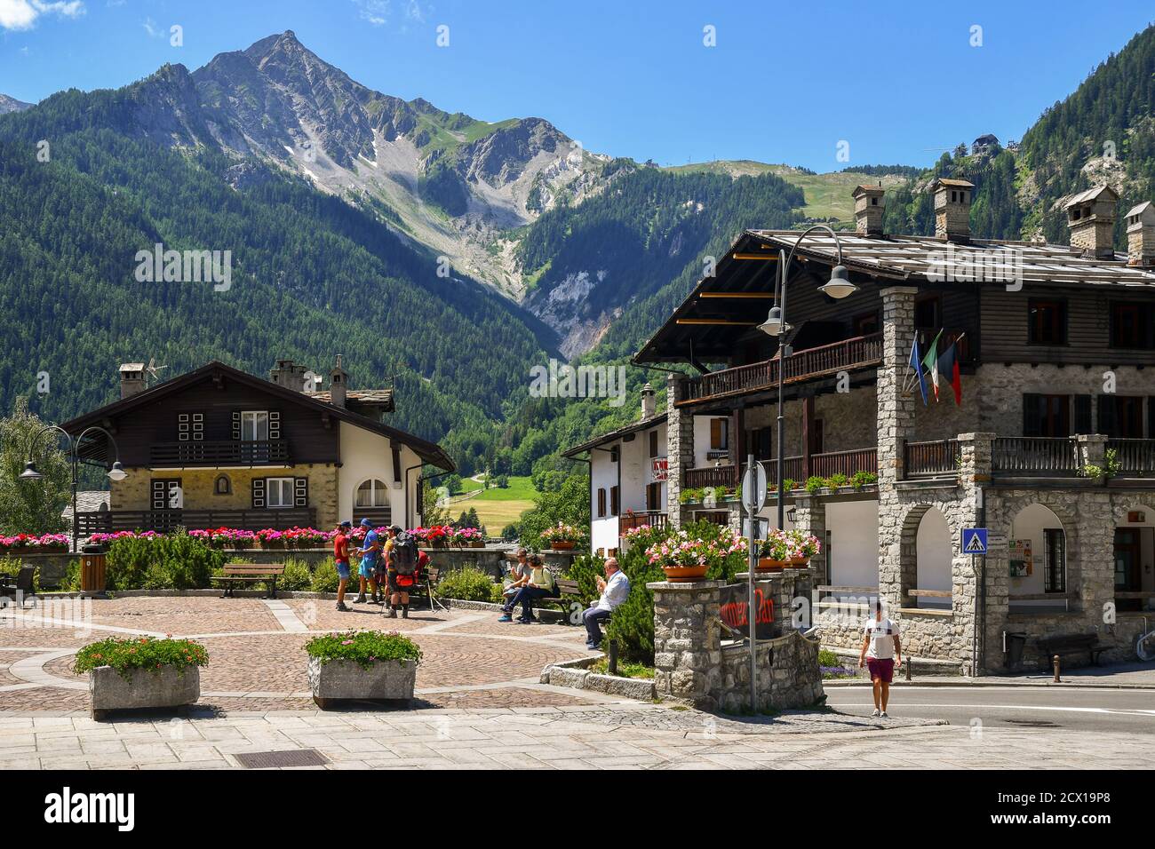 View of Brocherel square in the centre of the famous mountain town with people and backpackers in summer, Courmayeur, Aosta Valley, Italy Stock Photo