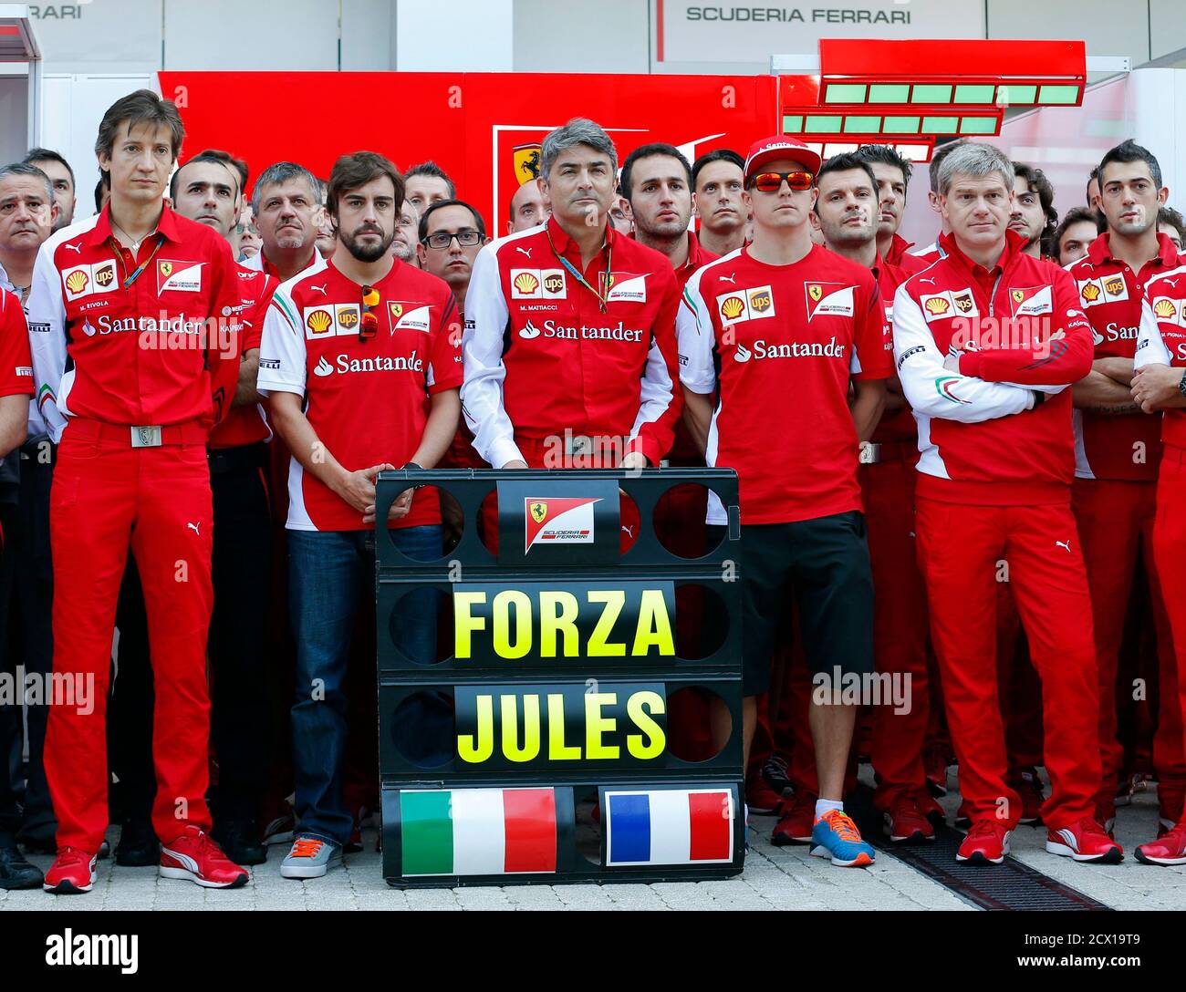 Members of Ferrari Formula One team pose with a sign in support of Marussia Formula One driver Jules Bianchi of France before the first Russian Grand Prix in Sochi October 12, 2014. Formula One drivers have backed proposals to introduce a 'virtual safety car' or automatic speed limiter that would force the entire field to slow when yellow warning flags are waved. The idea was raised by race director Charlie Whiting at the Russian Grand Prix on Saturday as one of the measures being considered following Bianchi's horrific crash in Japan last weekend. REUTERS/Laszlo Balogh (RUSSIA - Tags: SPORT M Stock Photo