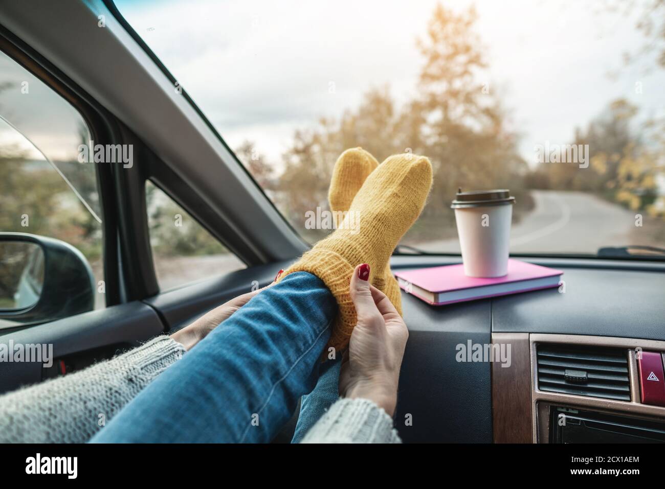Woman in a car in warm woolen yellow socks on the car dashboard. Cozy