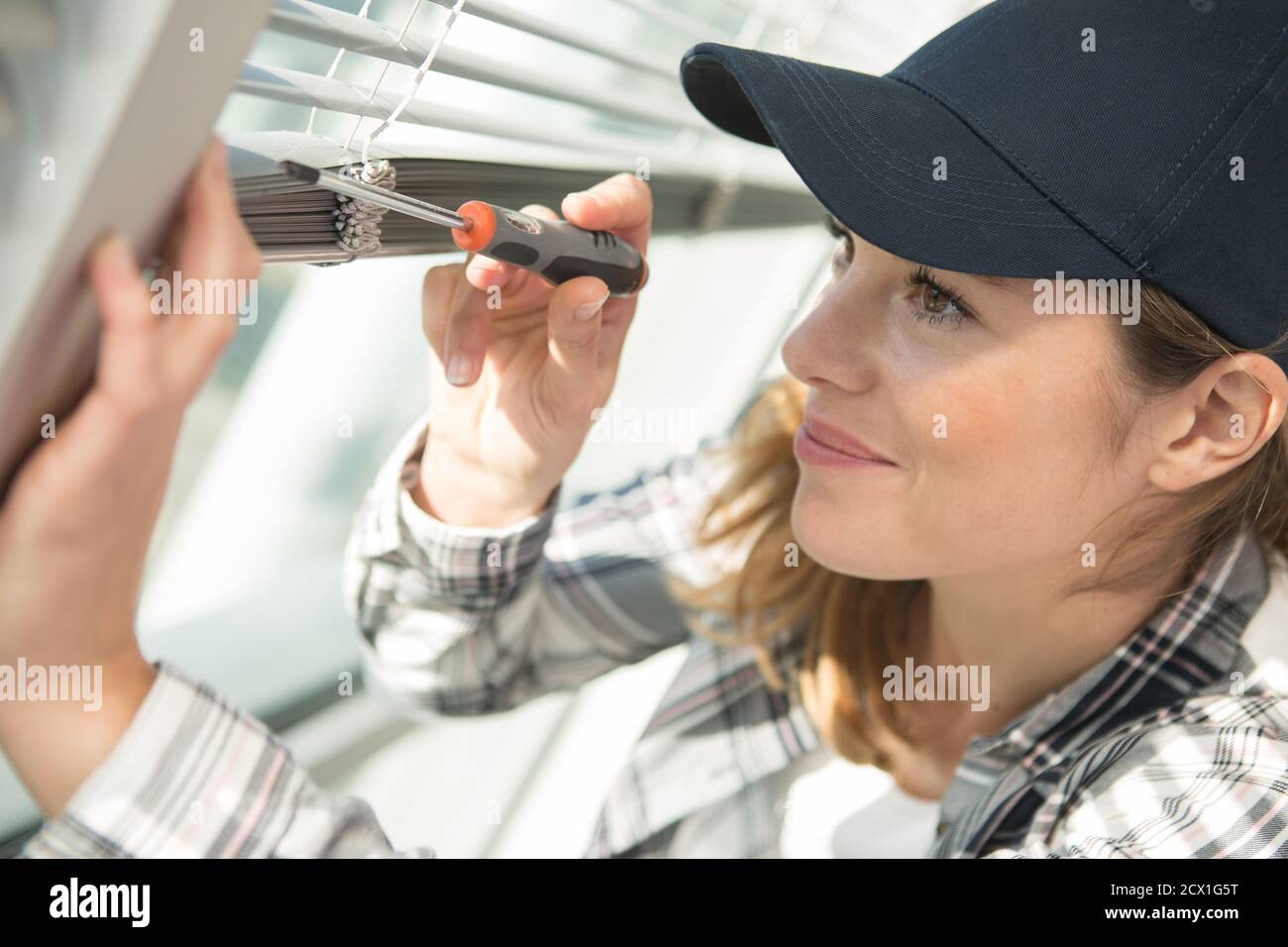 woman installing blinds with screwdriver Stock Photo