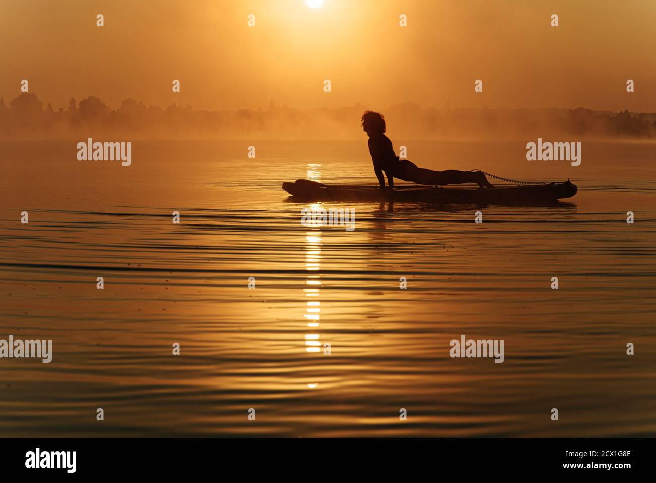 Young man doing plank exercise on paddle board Stock Photo
