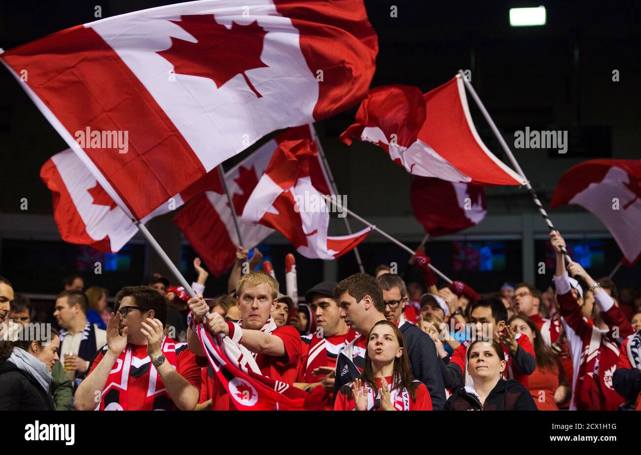 Canadian fans wave flags prior to their CONCACAF women's Olympic qualifying soccer match against Cuba in Vancouver, British Columbia January 21, 2012. REUTERS/Andy Clark (CANADA - Tags: SPORT SOCCER OLYMPICS) Stock Photo