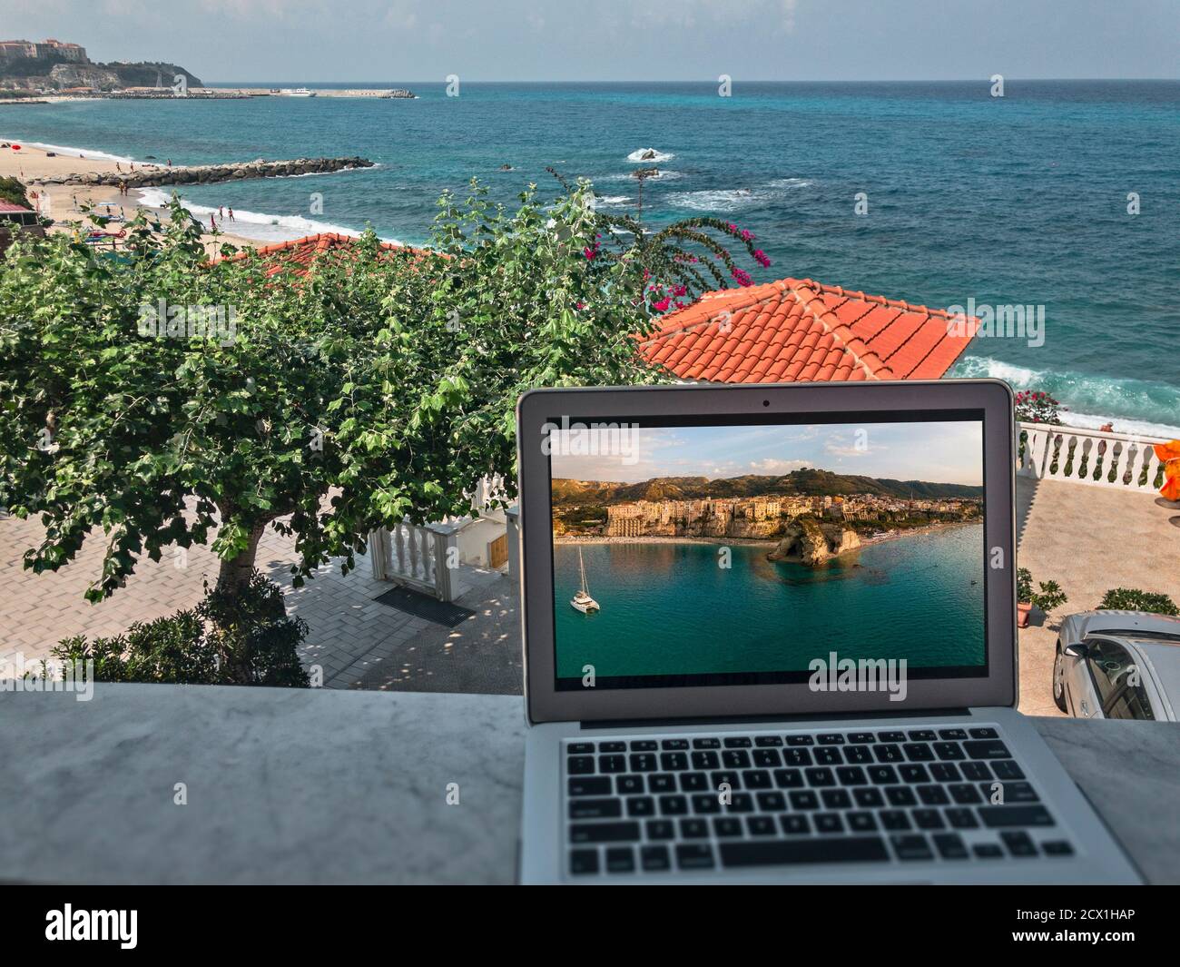 Smart working, growth of working productivity. Panoramic view of Tropea, Italy, work from home. Computer and connection. Stock Photo