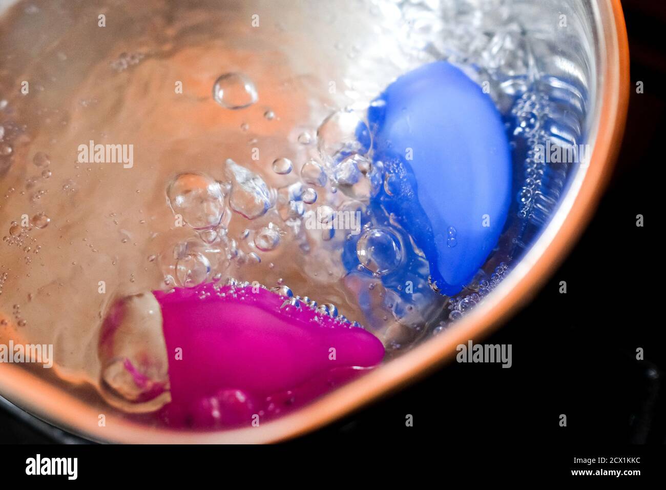 Boil the menstrual cups in a saucepan. Water bubbles visible. Stock Photo