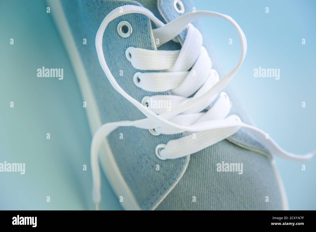 Blue sneakers with white laces on a light blue background. Trendy ...