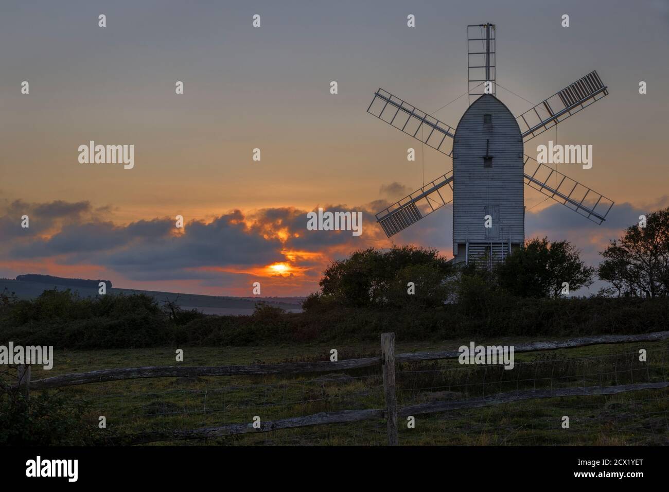 Watching the sun go down behind Ashcombe mill and the south downs on the Kingston Ridge near Lewes in east Sussex south east England Stock Photo