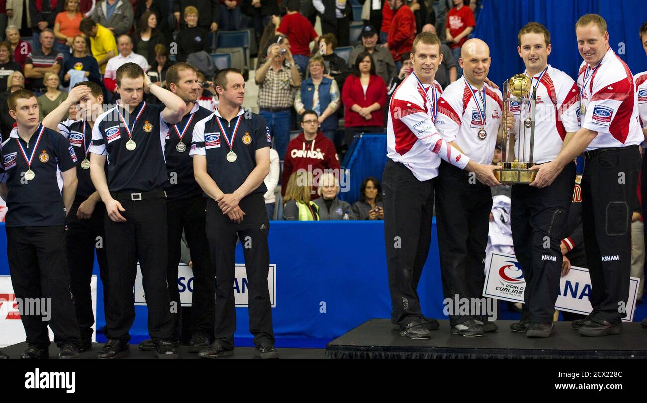 Members of Scotland look over at the Canadians with the world trophy after winning the gold medal game at the World Men's Curling Championships in Regina, Saskatchewan April 10, 2011. Canadian players are Jeff Stoughtan (4th R) , Jon Mead, Reid Carruthers and Steve Gould (R). Scotland players are (L-R) Greg Drummond, Scott Andrews, Michael Goodfellow, Duncan Fernie and coach Ron Brewster. REUTERS/Andy Clark    (CANADA - Tags: SPORT CURLING) Stock Photo