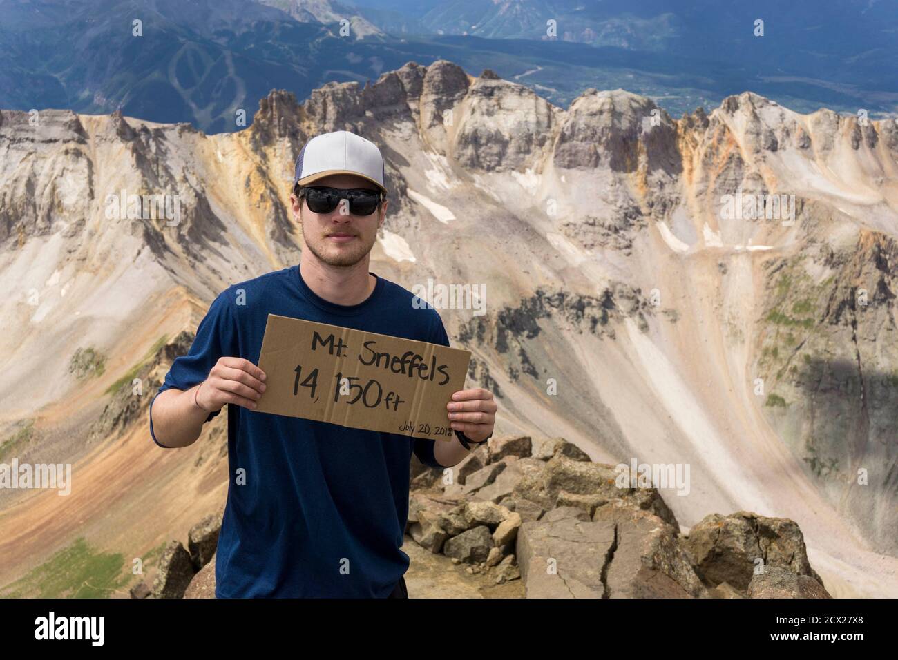 Portrait of male hiker standing with sign on Mount Sneffels Stock Photo