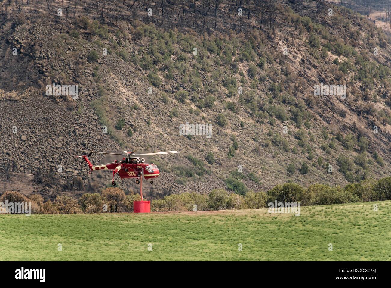 Military helicopter with fire retardant against mountain Stock Photo