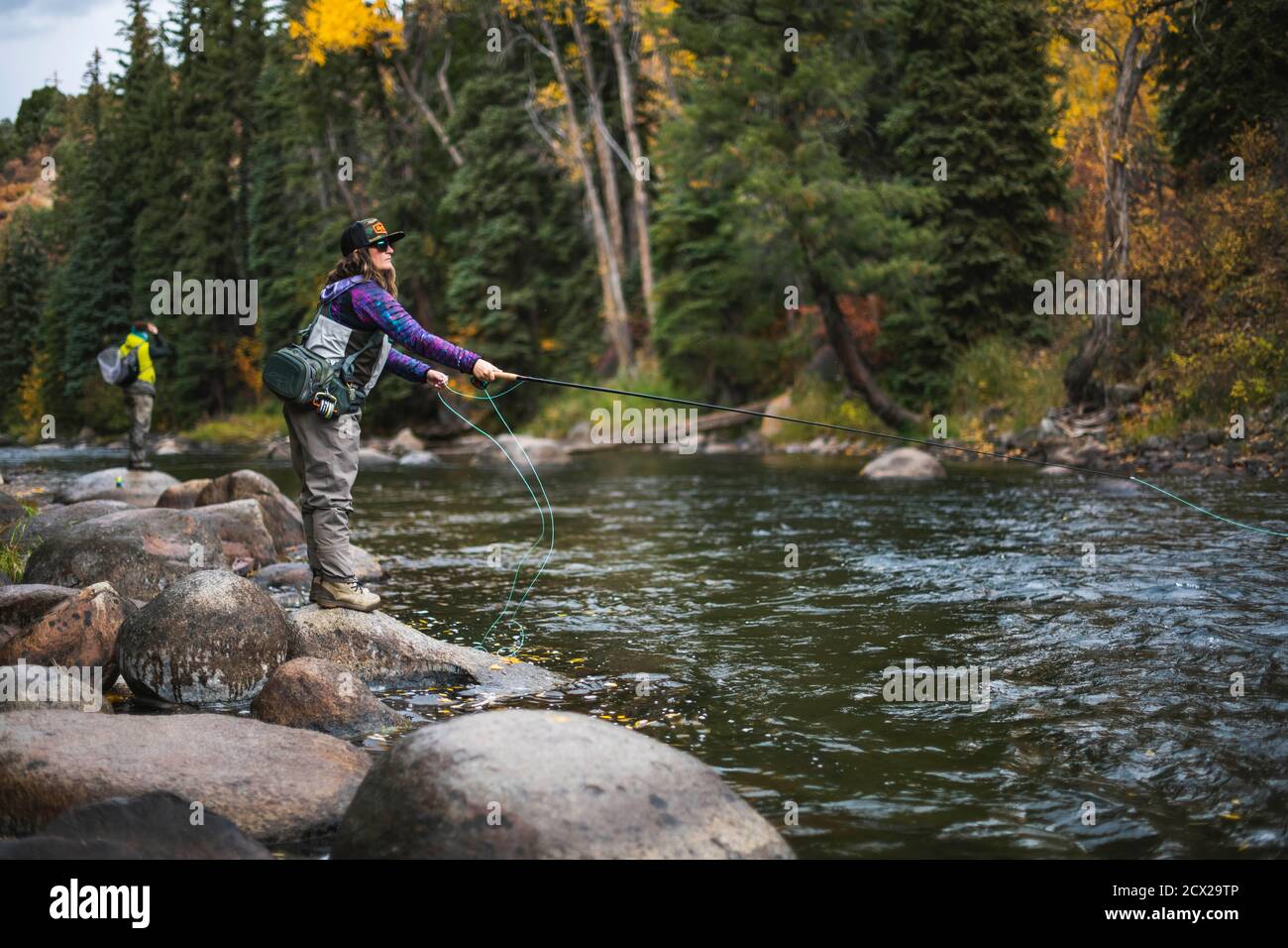 Side view of woman fly fishing while standing on rock at Roaring Fork