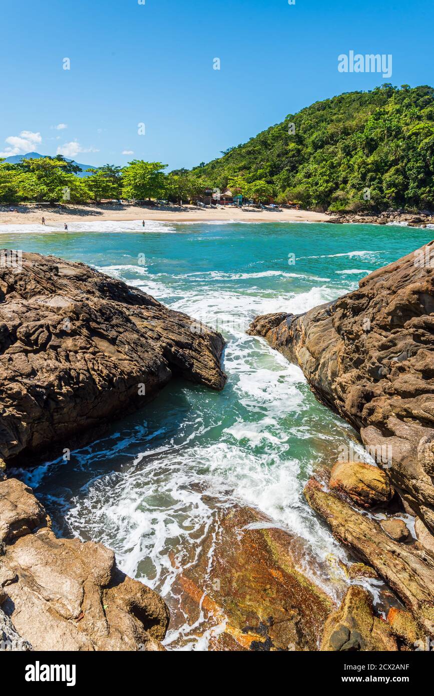 Small beach in a wild tropical landscape viewed from distance from rocks on the shore Stock Photo