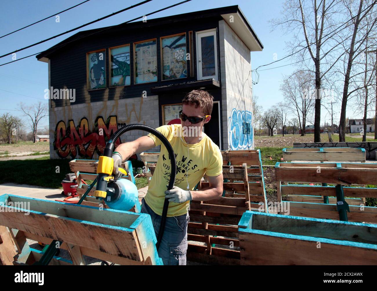 Darin McLeskey, 22-years-old, spray paints wooden pallets he plans to use to build a fence around a garden next to one of the properties he purchased and plans on refurbishing in Detroit, Michigan May 1, 2013. Low property prices in Detroit in the wake of the housing crash in 2008 have lured investors from California to China. Speculators bank on high returns despite a financial crisis so dire Detroit's state-appointed emergency manager, Kevyn Orr, has cited a 50-50 chance the city will file for bankruptcy. Picture taken May 1, 2013. To go with USA-DETROIT/HOUSING      REUTERS/ Rebecca Cook  ( Stock Photo